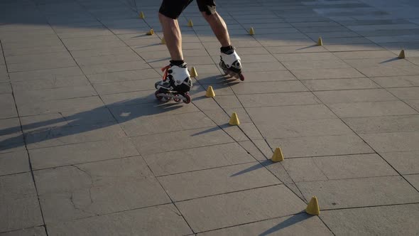 Close-up Legs of a Young Man Is Professionally Skating Between Cones on a Nice Evening Sunset in a