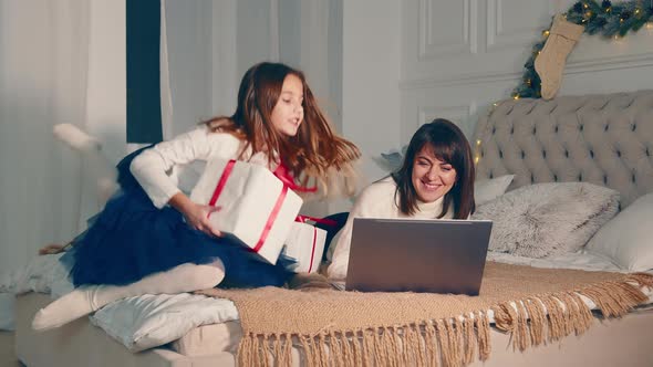 Happy Mom with Kids on Christmas Day Showing Presents to Dad Via Laptop
