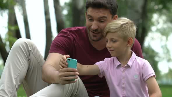 Male and Child Taking Selfies, Mugging for Camera, Family Leisure With Gadgets