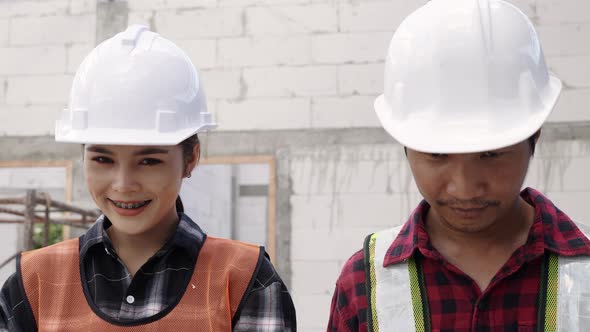 Portrait of Asian construction worker at building site smiling at camera