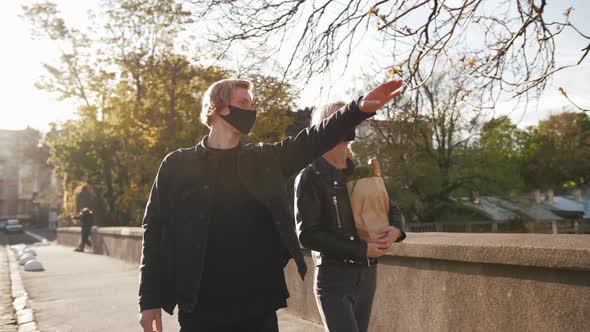 Portrait of Happy Young Couple in Protective Masks Walking Outdoors in Old City Center with Grocery