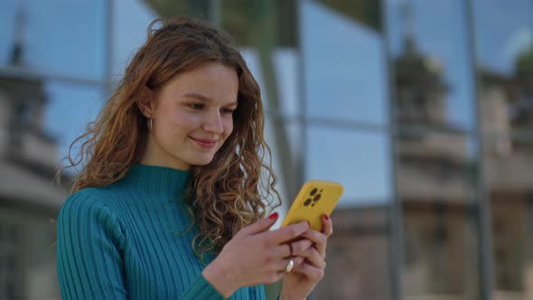 Smiling Woman Typing Messages on Smartphone Outdoors