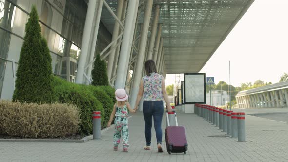Mother and Daughter Walking To Airport. Woman Carrying Suitcase Bag. Child and Mom Vacation. Rear