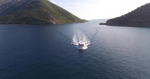 White Motorboat Sails on the Sea Past the Mountainous Coast