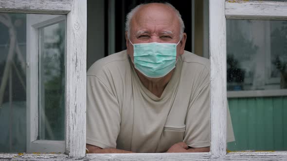 Portrait Of Adult Caucasian Man In Protective Medical Mask Looking Out Of Window