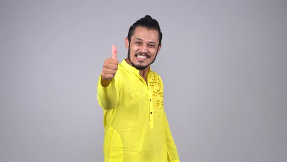 Happy Indian man showing thumbs up to the camera in an Indian outfit
