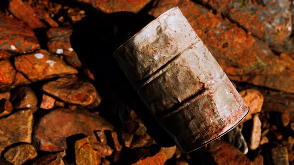 Rusty Destroyed Metal Barrel on Beach Rocks