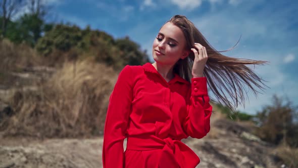 Portrait of attractive young woman. Gorgeous female in red dress standing among nature