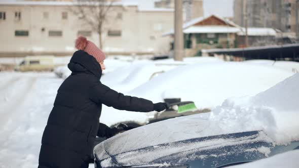 Sweep Snow From Automobile With Brushes In Winter. Scraping Ice. Scratching Ice From Car Window.