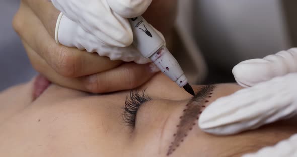 Asian woman having microblading eyebrows in a beauty salon