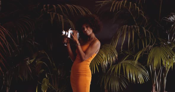 Woman With Afro Hair In Orange Dress Using Vintage 8Mm Camera