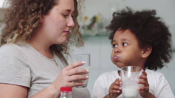 White Mother and Her Mixed Black Daughter Drinking Milk at the Kitchen
