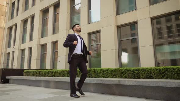 Happy Businessman Is Dancing on the Street Near the Office Center Wearing Suit Celebrating