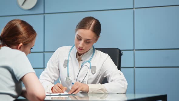 Lady doctor in white coat with stethoscope writes prescription