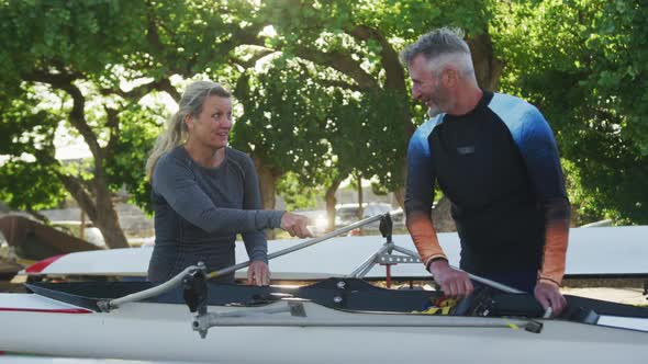 Senior caucasian man and woman preparing rowing boat for the water