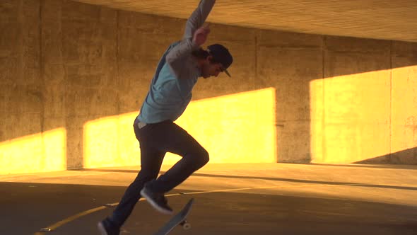 Silhouette of a young man skateboarding in a parking garage at sunset.