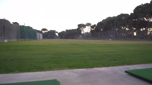 Practice area of ​​a golf course, the camera lowers slowly and changes the focus to an empty ball cu