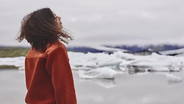 Curly Female Tourist Standing in the Midst of Glacial Fields in Iceland