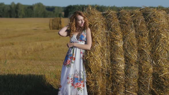 Portrait of Attractive Young Redhead Woman Standing Near Hay