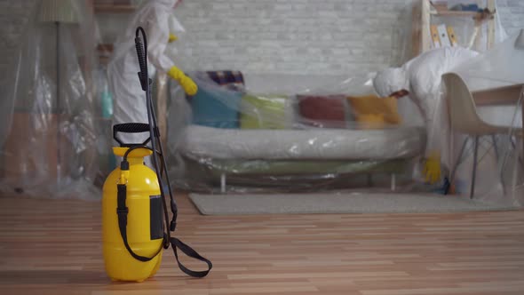 Workers in Protective Suits Shielding Cellophane Wrap Furniture