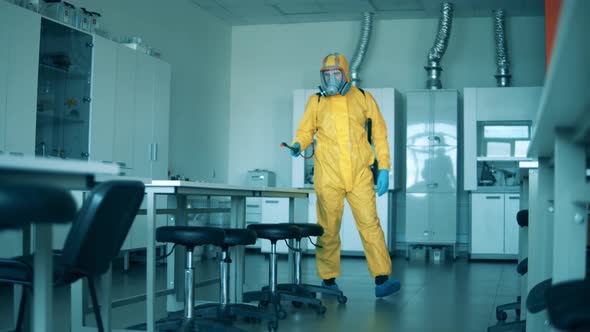 One Man in Yellow Hazmat Disinfects Room.