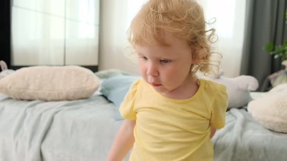 Cheerful Little Child Girl in a Yellow Tshirt is Unhappy That She is Being Removed and Covers the