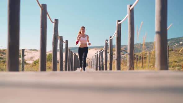 Athletic Sportswoman Running on Beach Wooden Path Slow Motion Tracking Shot