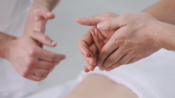 Close Up Masseurs Rubbing Hands with Massage Oil