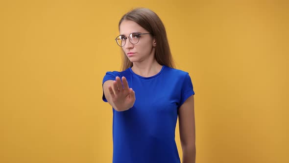 Portrait of Strict Woman Frown Waving Hand Gesture Stop No Posing Isolated on Orange Studio