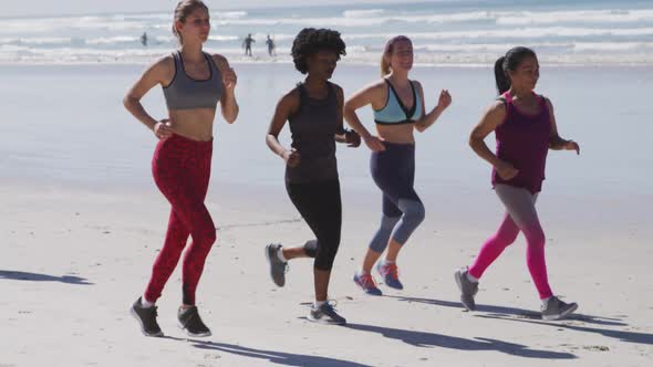 Multi-ethnic group of women running on the beach and blue sky background