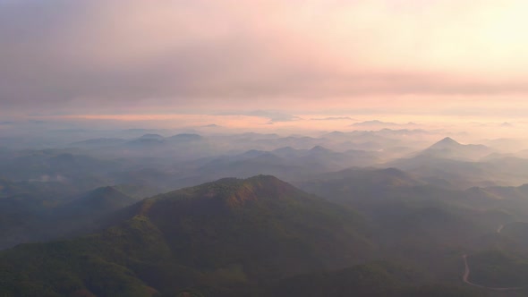 4K Scenic flight over beautiful mountain scape with bright sky and clouds