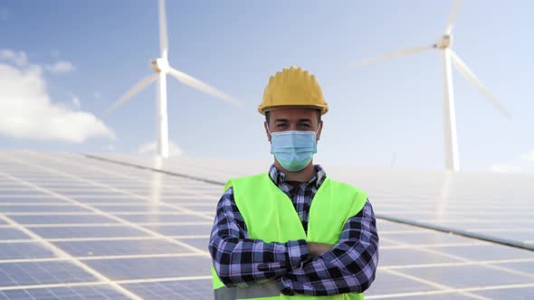 Young engineer working for alternative energy with wind turbine and solar panel