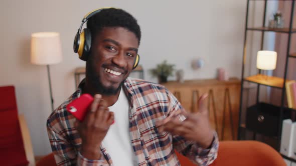 Pretty African American Man in Headphones Listening Music Dancing Singing in Living Room at Home