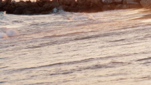 Sunset scene of foamy sea waves rolling in on the shore