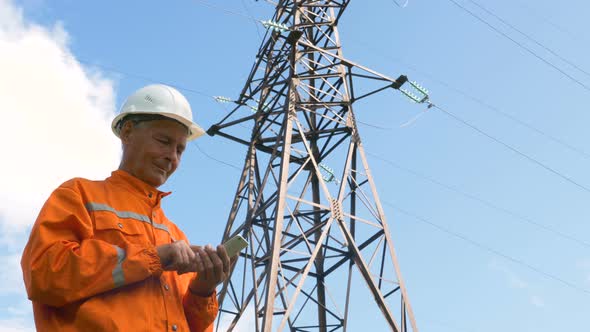 Senior Surveyor Puts Data in Smartphone By Power Lines Tower