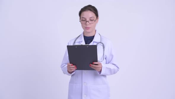 Happy Young Beautiful Woman Doctor Reading on Clipboard and Explaining Something