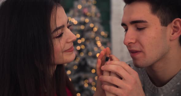 Close-up. The Guy Kisses the Girl's Hands Looking Her in the Eyes. Winter Sweaters