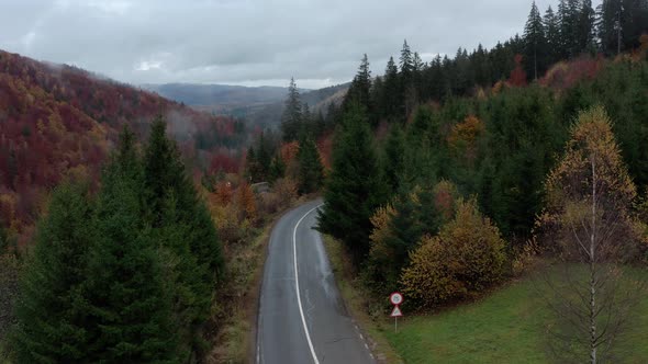 Mountain Road Through The Forest In Autumn In Romania. - aerial drone ascend