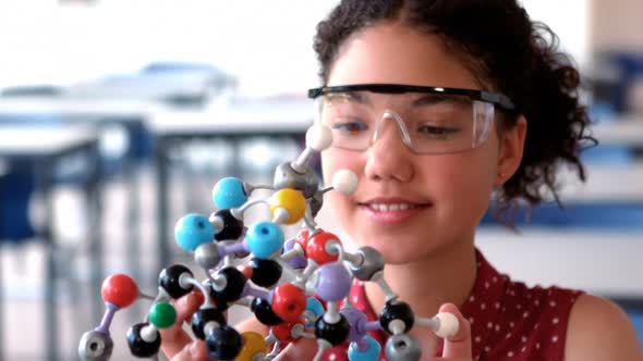 Attentive schoolgirl experimenting molecule model in laboratory