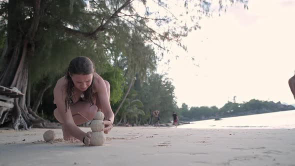 The Girl on the Beach Makes a Snowman From the Sand