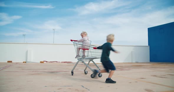 Kids Having Fun Playing with Supermarket Sopping Cart in Parking Outdoors