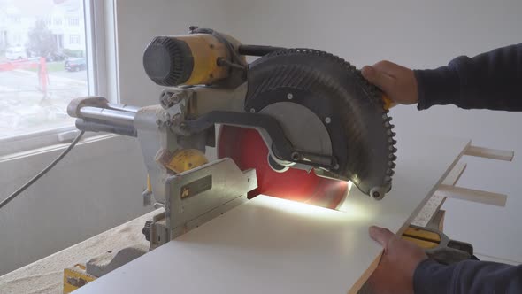 Carpenter at Work Using Circular Saw Cutting Wooden Shelf Board