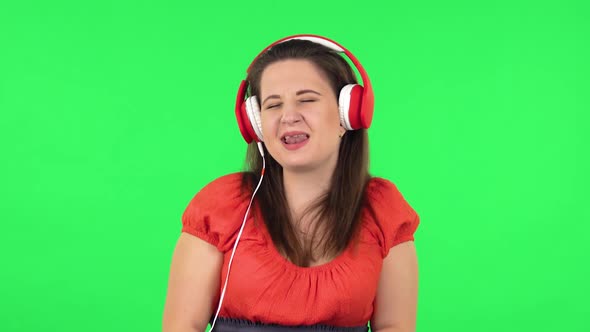 Portrait of Cute Girl Is Dancing and Enjoying Music in Big Red Headphones. Green Screen