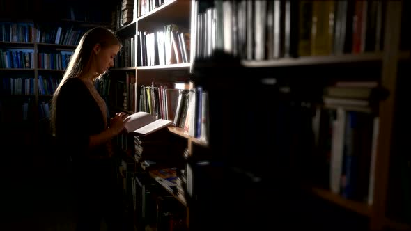 Pretty Young College Student in a Library, Chooses a Book