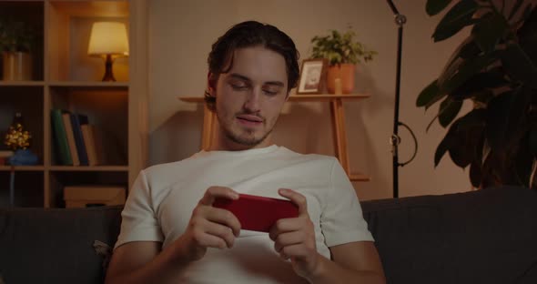 Crop View of Young Excited Man Playing Online Game While Sitting on Sofa at Home