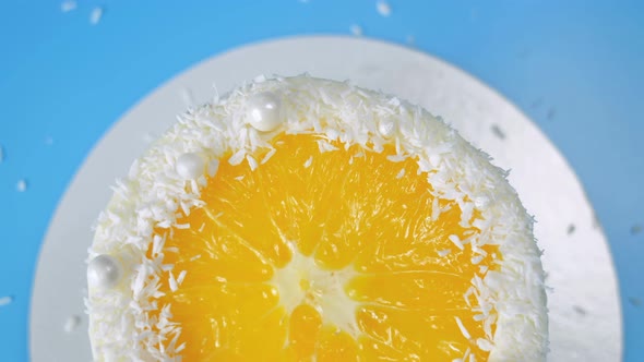 Cake with Orange and Coconut Shavings Spinning on a Blue Background