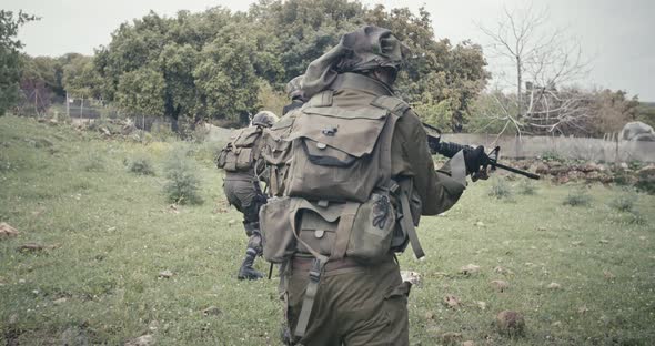 Squad of fully armed commando soldiers during combat in a forest scenery