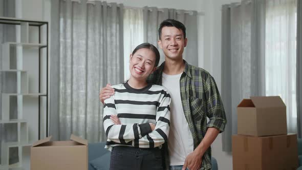 Smiling Young Asian Couple, Man's Arm Around Woman'S Shoulder, Posing To The Camera In A New House