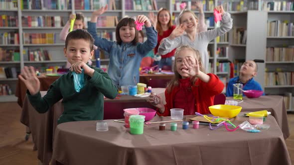 Happy Kids with Disabilities Waving Hands in Class