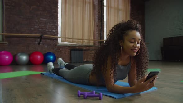 Lovely Woman with Cellphone Relaxing After Workout